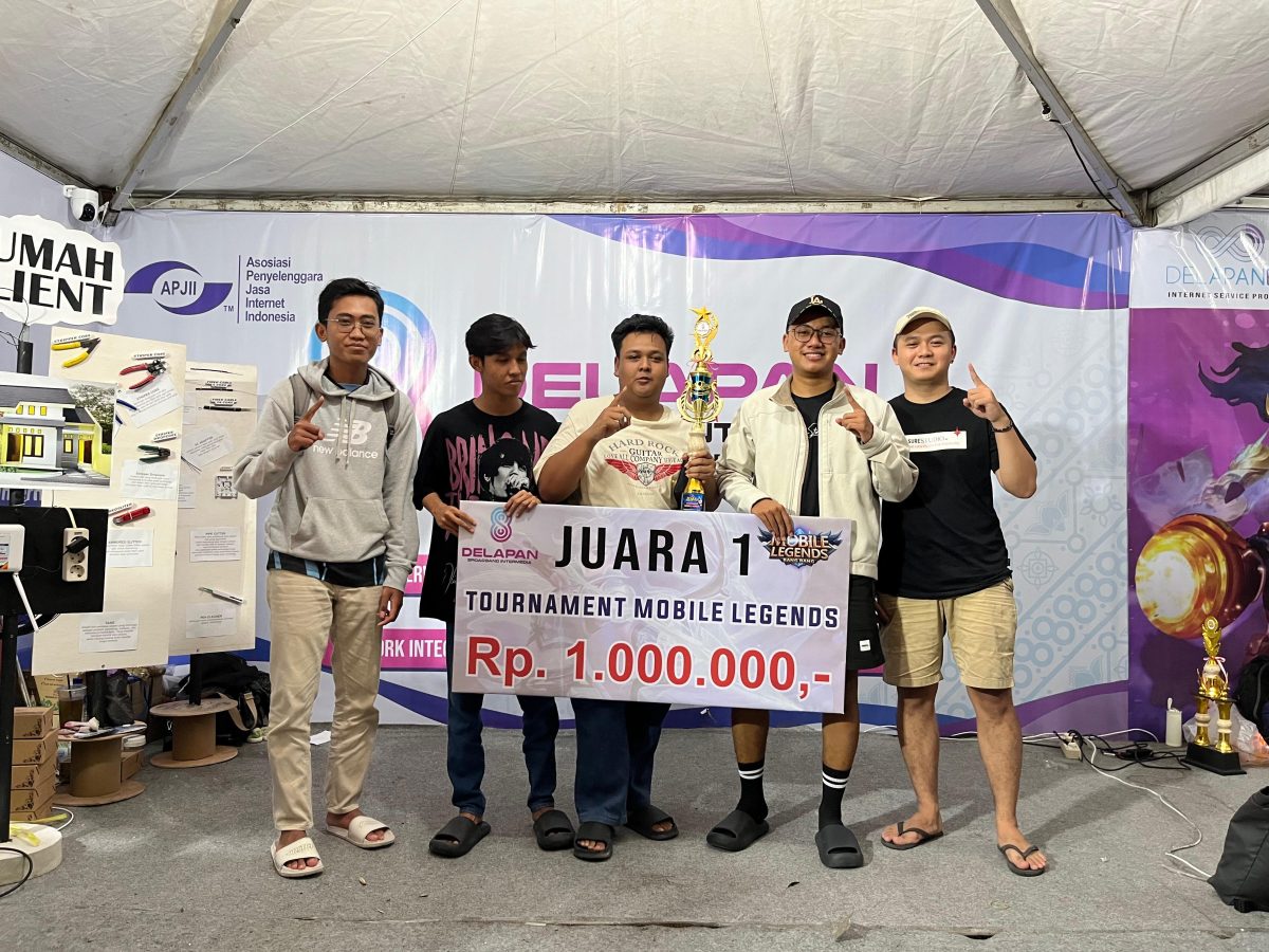 Tim pemenang Juara 1 Turnamen Mobile Legends DelapanBit berfoto bersama memegang piala dan banner hadiah utama