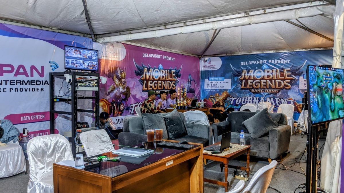 Suasana ruang setup turnamen Mobile Legends DelapanBit dengan perlengkapan streaming dan server