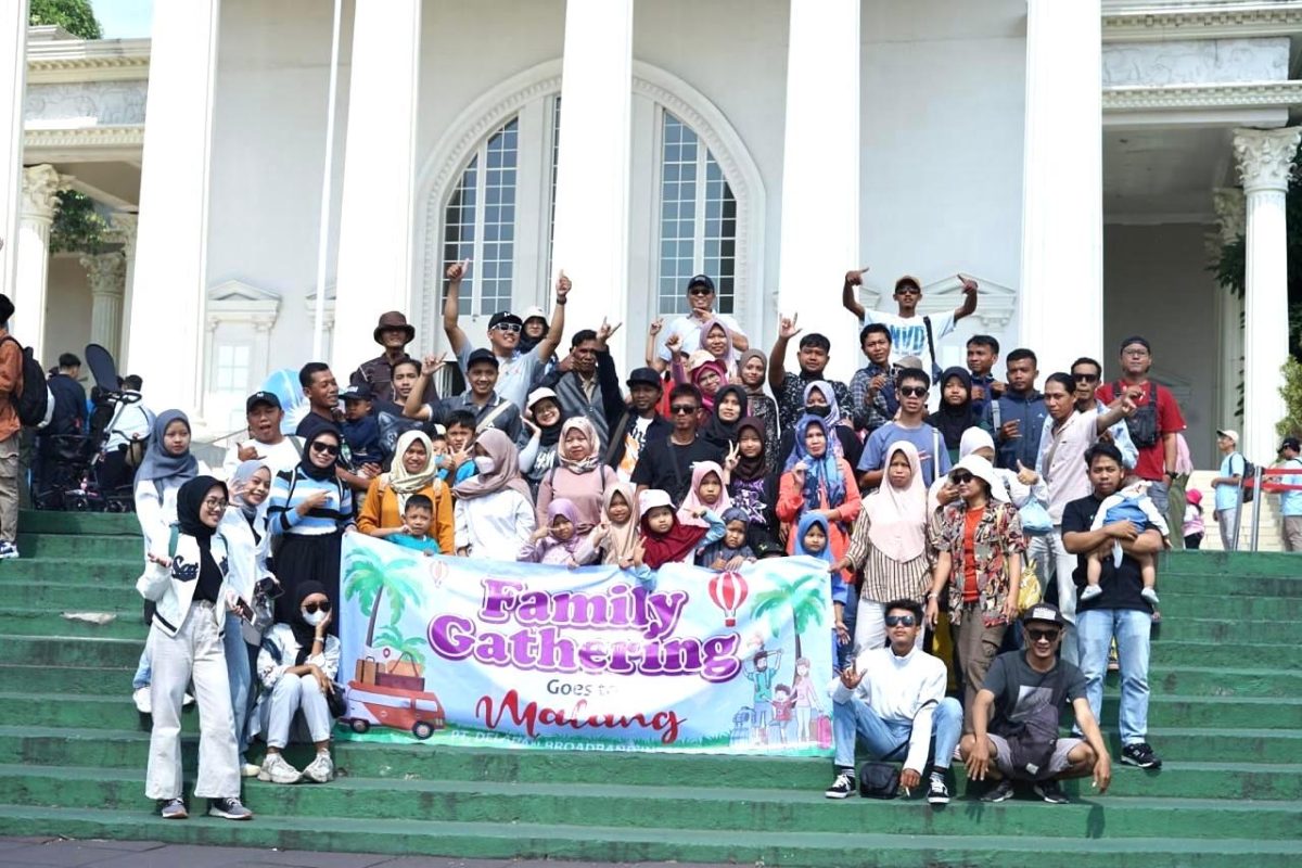 Keluarga besar DelapanBit berfoto bersama dengan banner Family Gathering Goes to Malang di tangga Museum Angkut