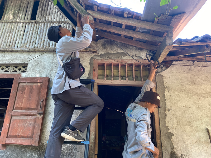 Teknisi menarik kabel drop core dari tiang menuju ke rumah pelanggan