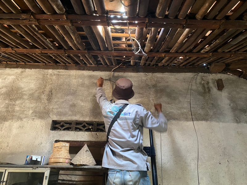 Teknisi memasukkan kabel jaringan menembus plafon rumah pelanggan