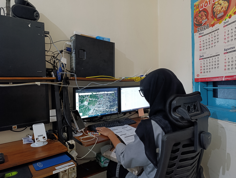 Teknisi memantau grafik pemetaan dan monitoring jaringan di monitor NOC