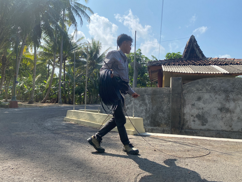 Teknisi membawa gulungan kabel drop core di jalan