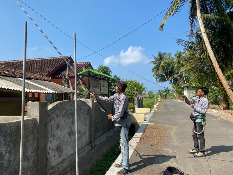 Teknisi menarik kabel udara serat optik melintasi jalan