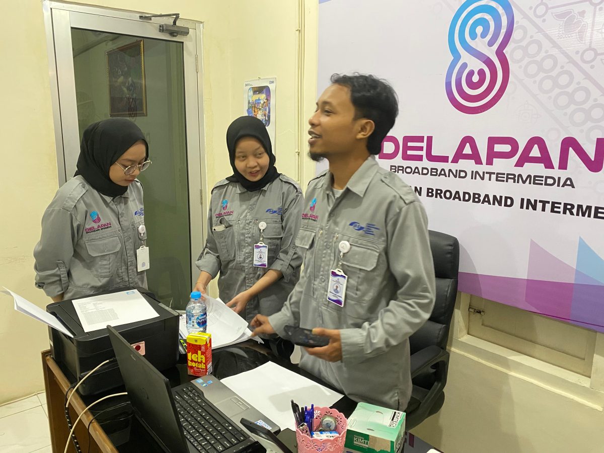 Staf kantor DelapanBit melakukan koordinasi dan diskusi dokumen di depan laptop