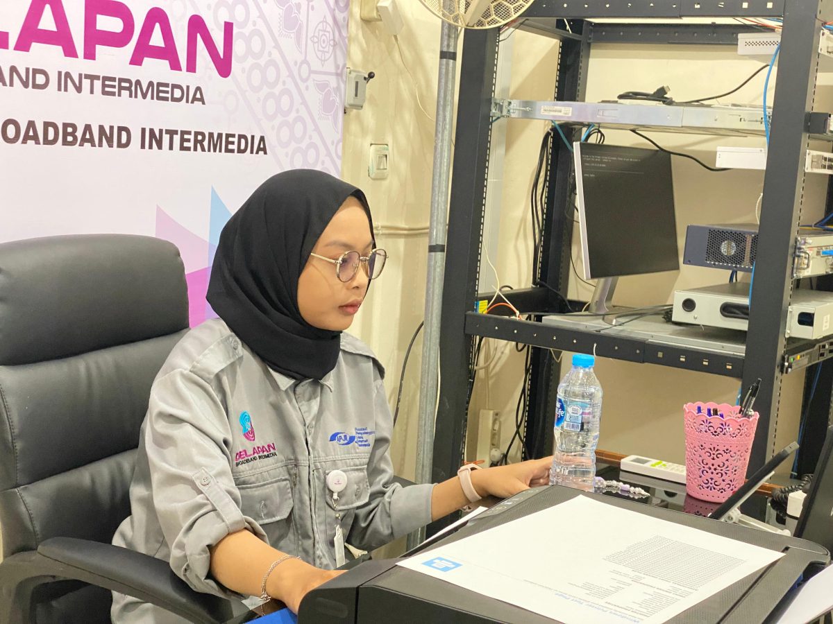 Staf administrasi wanita DelapanBit bekerja di depan komputer dekat perangkat server