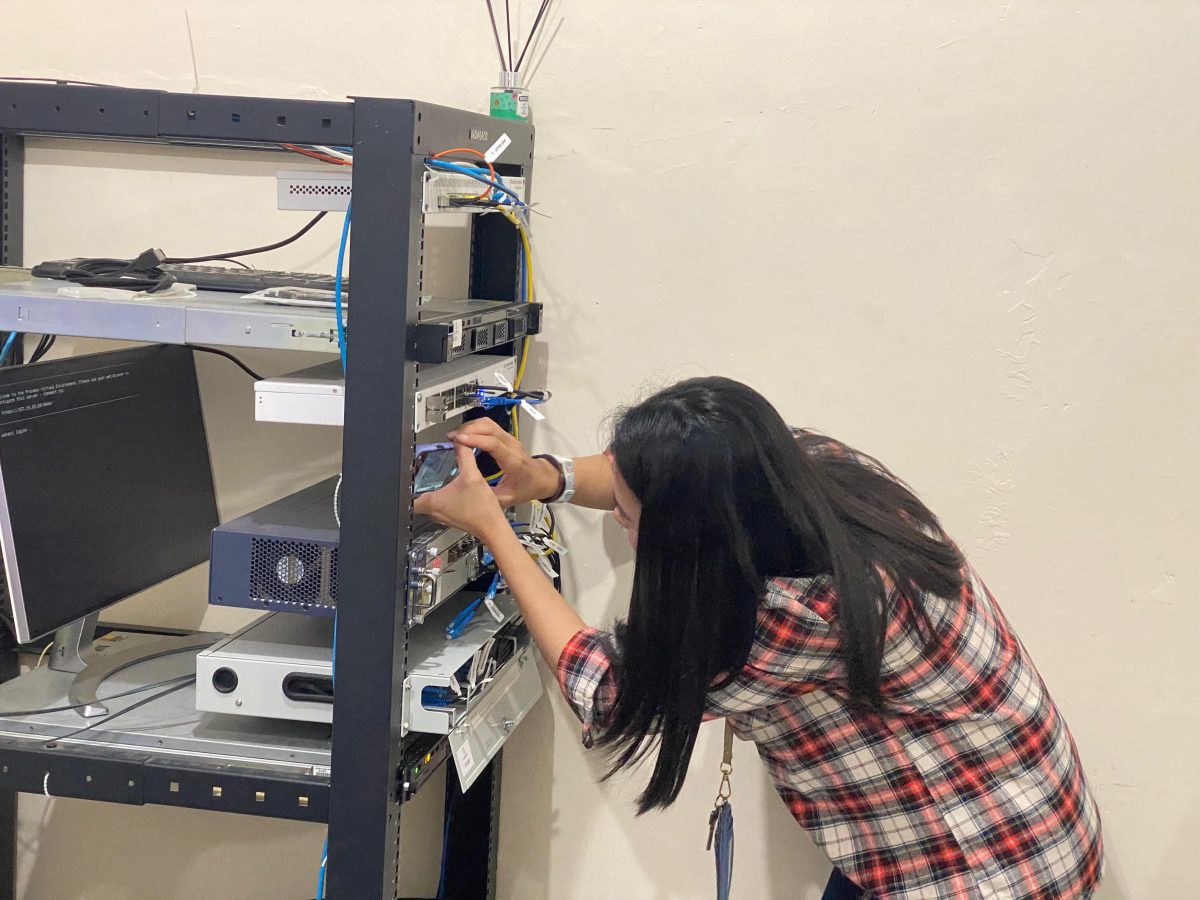 Teknisi wanita melakukan konfigurasi dan pemeliharaan perangkat server di rack
